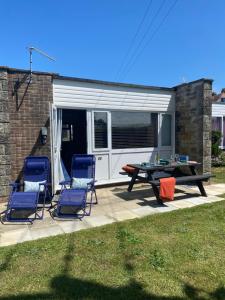 a patio with two chairs and a picnic table in front of a garage at Seagulls Rest in Isle of Wight