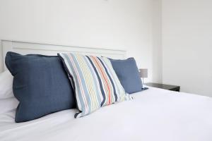 a white bed with blue pillows on top of it at Ideal Bath House by St James’s Park in Bath