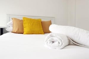 a bed with towels on it with a yellow pillow at Ideal Bath House by St James’s Park in Bath +53 photos
