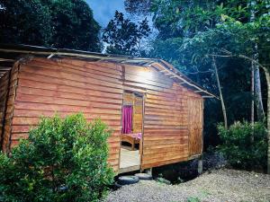 a wooden shed with a chair in the doorway at Won Happy Hotel - Kitulgala in Kitulgala