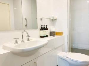 a white bathroom with a sink and a toilet at The Iceworks-overlooking Esplanade W Parking 2 Carscentral in Fremantle +24 photos