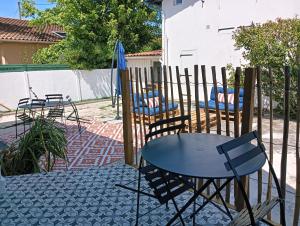 a patio with two chairs and a table and an umbrella at La charmante Albertine villa proche port in Arcachon +1 photo