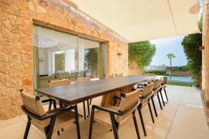 an outdoor dining room with a large wooden table and chairs at Villa Zelmar - Tranquility and Privacy in Cala Conta in Sant Josep de Sa Talaia