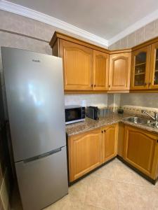 a kitchen with a white refrigerator and wooden cabinets at Cozy 1 Bed Flat in Monte Gordo