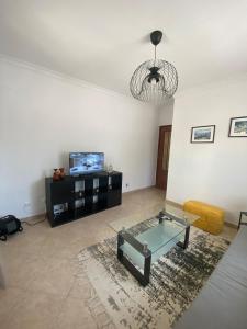 a living room with a glass table and a tv at Cozy 1 Bed Flat in Monte Gordo