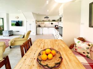 a kitchen and living room with a wooden table with oranges on it at The Barn at Orford Lodge by The Suffolk Cottage Collection in Orford