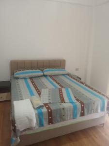 a bed with a striped comforter in a room at Beta Holidays in Vlorë