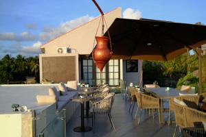 a patio with tables and chairs and an umbrella at Casa Narrow Villa in Nembrala