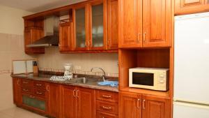 a kitchen with wooden cabinets and a sink and a microwave at Apt. Heliconia Nº 5 in La Playa Calera