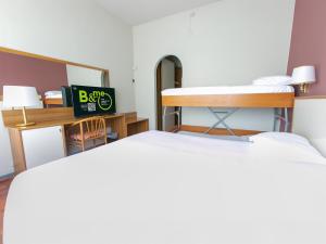 a room with two beds and a desk with a mirror at B&B HOTEL Riviera Celle Ligure in Celle Ligure