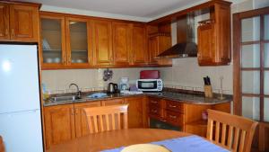 een keuken met houten kasten en een tafel met een magnetron bij Apartamento Heliconia 1 in Valle Gran Rey