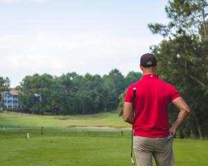 a man in a red shirt standing on a golf course at Maison de vacances Des Tucs Dou in Seignosse
