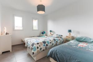 Un dormitorio con dos camas y dos ventanas. en Appartement Lumineux avec Terrasse, en Seignosse