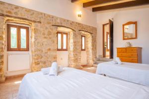 a bedroom with two beds and a stone wall at Sa Corterada in El Port de la Selva +30 photos
