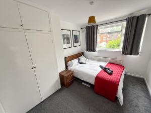 a small bedroom with a bed and a red ottoman at Bassetts House - Contractor ready! in Farnborough