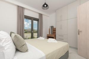 ein weißes Schlafzimmer mit einem Bett und einem Fenster in der Unterkunft Zante Escape Suites by "elite" in Laganas