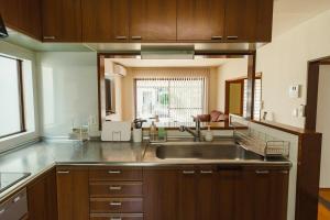 a kitchen with a stainless steel sink and wooden cabinets at Kumamoto Airport Villa 5 mins from Kumamoto Airport in Nishiharamura