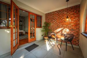 a patio with a table and chairs and a brick wall at Telos at Connor in Bloemfontein