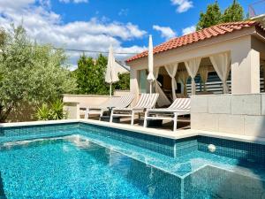 a swimming pool with chairs and a house at Apartments Villa A - Heating Pool in Trogir