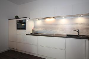 a white kitchen with a sink and a microwave at Wohnen am Yachthafen W46 in Cuxhaven