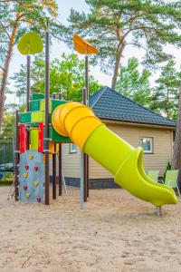 a playground with a yellow slide in the sand at Kolorowe Domki in Pobierowo