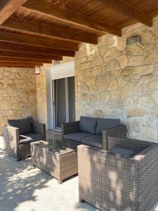 a patio with wicker furniture and a stone wall at Elani villa''s in Elani