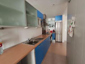 a kitchen with blue cabinets and a stainless steel refrigerator at LaCalaSuit in Benidorm
