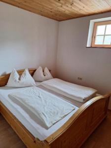 a bedroom with a wooden bed with white sheets at Tauernbergalm in Heiligenblut