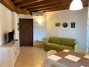 a living room with a green couch and a table at The Artist - Apartments with Private Garden in Residence with Pool in Manerba del Garda