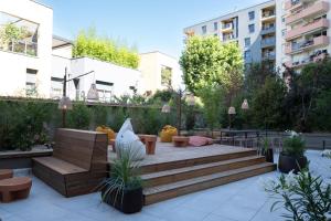 a garden with a wooden bench and tables and buildings at Hotel Oceania Lyon in Lyon