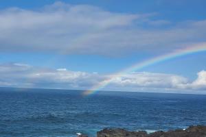 a rainbow in the sky over the ocean at Oceanfront studio see whales and dolphins in Pahoa