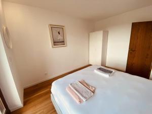 a white bedroom with two towels on a bed at Helles Apartment Bergblick Nähe Messe Frankfurt in Bad Soden am Taunus