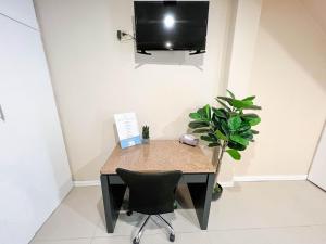 a desk with a chair and a tv on a wall at Stacys Place #4 Studio Apartment in Port-of-Spain