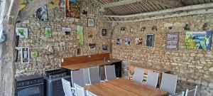 a restaurant with a table and chairs and a stone wall at Le havre de faye in Savigny-sous-Faye