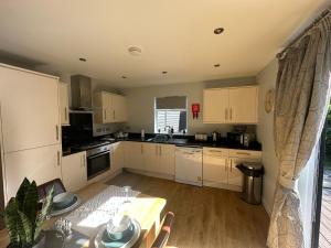 a kitchen with white cabinets and a table and a dining room at 5A Retallack Resort & Spa in Saint Columb Major