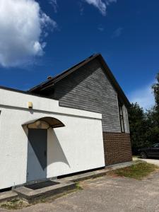 a white building with a door on the side of it at Apartamenti Upesgrīvā in Upesgrīva