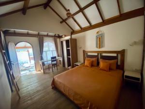 a bedroom with a large bed with orange pillows at Gaia cottages in Gili Trawangan