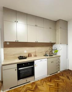 a kitchen with white cabinets and a stove top oven at Apartman Olivia in Berane