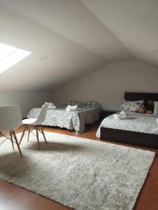 a bedroom with two beds and a chair and a rug at Esposende Private Terrace Flat in Outeiro