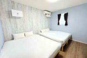 two beds in a room with white sheets at グランディオーソ沖縄プールヴィラ恩納4 in Onna +36 photos