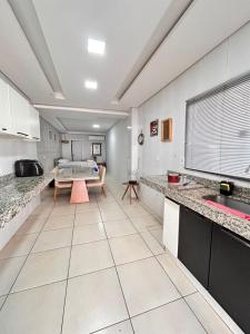 una cucina con banconi bianchi e un tavolo di Loft 03 - Zona Sul Prox UMC, Pátio Vinhedos e Shopping a Uberlândia