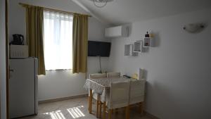a dining room with a table and chairs and a window at Apartmani Sanja in Vrsi