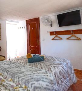 Un dormitorio con una cama con un televisor en la pared. en El Azahar, en Sevilla