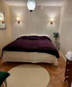 a bedroom with a large bed with a purple blanket at Lovely small room with a double bed no window in a charming Båstad villa prime location with terrace in Båstad