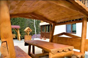 a wooden pavilion with a wooden bench in a yard at Road's End Moieciu De Sus in Moieciu de Sus