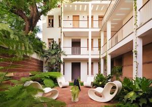 a courtyard of a building with white chairs and trees at Billini Hotel, Historic Luxury in Santo Domingo