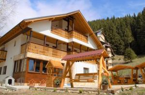 a large wooden house with a balcony at Road's End Moieciu De Sus in Moieciu de Sus