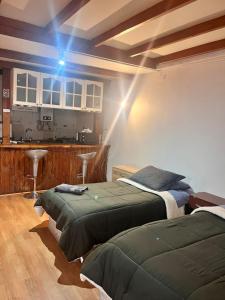 two beds sitting in a room with a kitchen at DEPARTAMENTOS CLIMENT in Osorno