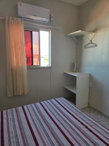 a bedroom with a bed and a window and a desk at Residencial Vicente Mota Neto in Fortaleza