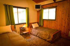 a bedroom with two beds and two windows with green curtains at The Quail's Nest Retreat in Point Reyes Station